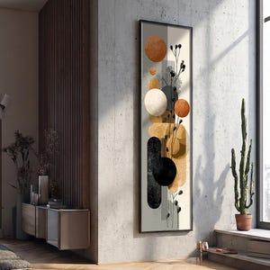 Può includere: Stampa artistica astratta incorniciata. L'opera presenta una composizione verticale di forme geometriche, tra cui cerchi e ovali nei toni dell'arancione, nero e beige. Una sottile linea nera e uno sfondo neutro completano il design.