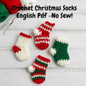 May include: Four miniature crochet Christmas stockings in red, white, and green. The text "Crochet Christmas Socks English Pdf - No Sew!" is at the top of the image. The stockings are arranged on a light wood surface.