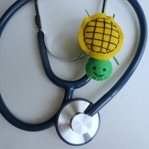 May include: A blue stethoscope with a yellow and green felt turtle toy attached to it.