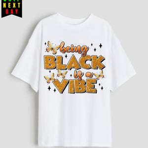 May include: White t-shirt with a gold glitter design that says "being black is a vibe" with butterfly accents.