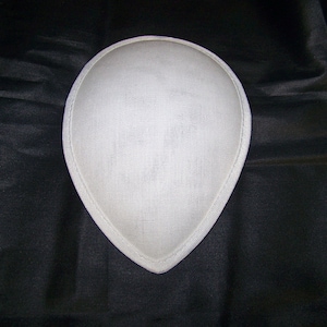 May include: A white fabric hat shaped like a teardrop, with a smooth, slightly textured surface.