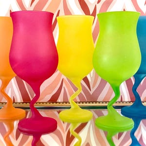 May include: Five frosted glass cocktail glasses in different colors: orange, pink, yellow, green, and blue. The glasses have a unique twisted stem design.