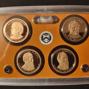 May include: A set of gold-colored coins featuring portraits of U.S. Presidents Andrew Johnson, James A. Garfield, Rutherford B. Hayes, and Ulysses S. Grant. The coins are displayed in a clear plastic case with an orange background.