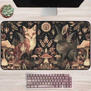 May include: A decorative desk mat featuring a fox and a rabbit amidst a forest scene with mushrooms and foliage. The color palette includes shades of brown, beige, and black. A keyboard is visible at the bottom of the image.