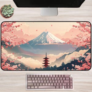 May include: A rectangular desk mat featuring a Japanese landscape with Mount Fuji, cherry blossoms, and a pagoda. The color palette includes pink, blue, and white. A keyboard is at the bottom. A succulent plant in a small pot is on the left.