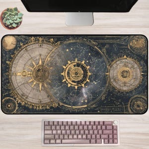 May include: A large rectangular desk mat featuring a celestial map design in shades of gold and navy blue. The mat has intricate details of constellations, compasses, and celestial bodies. A mauve keyboard sits below the mat, and a succulent plant is in the upper left corner.