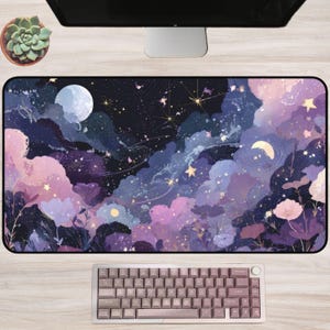Puede incluir: Una alfombrilla de escritorio rectangular con un diseño de cielo nocturno celestial, nubes púrpuras y rosas, una luna llena, una luna creciente y estrellas dispersas. La ilustración incluye elementos florales estilizados en lavanda y rosa.