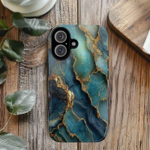 May include: A smartphone case with a teal and gold marble design. The case features a swirling pattern of teal and blue hues, accented with gold veins. The case has a camera cutout with two lenses.