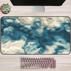 May include: A large rectangular desk mat with a swirling blue and white abstract design. A keyboard with pink keycaps is at the bottom, and a computer monitor is at the top. A small potted succulent is in the upper left corner.
