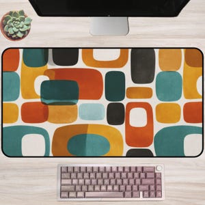 May include: A rectangular desk mat with a mid-century modern design. The mat features a pattern of colorful, rounded rectangles in teal, orange, yellow, black, and gray on a white background. A keyboard sits at the bottom.
