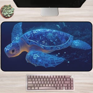 May include: A rectangular desk mat featuring a glowing blue sea turtle design. The turtle has intricate patterns and is set against a dark blue background. A keyboard and computer monitor are visible.
