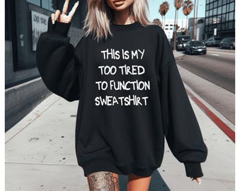 面白い疲れた言葉がプリントされたスウェットシャツ。居心地の良いのんびりとした一日の雰囲気。おうち時間にぴったり。ユーモアたっぷりのギフトに最適。快適なリラックスフィットのパーカー。