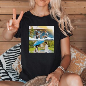 May include: A black t-shirt with a graphic of two scenes from the Korean drama "Lovely Runner". The top scene shows a couple walking away from each other, and the bottom scene shows a couple walking together under an umbrella.