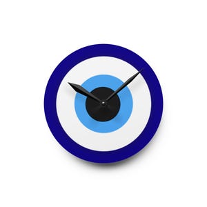 Puede incluir: Un reloj de pared redondo con un diseño de ojo turco azul y blanco. La esfera del reloj presenta círculos concéntricos azules, blancos y negros. Las manecillas negras indican la hora. Es un artículo decorativo.