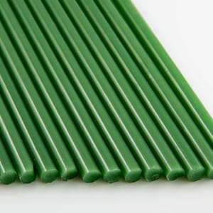 Könnte beinhalten: Nahaufnahme eines Bündels grüner Wachsstangen. Die Stangen sind in einer Reihe angeordnet und alle gleich groß und gleich geformt.