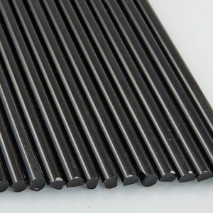 Könnte beinhalten: Nahaufnahme eines Bündels schwarzer Klebesticks. Die Sticks sind in einer Reihe angeordnet und alle gleich groß.