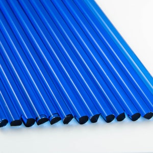 Könnte beinhalten: Eine Gruppe von 12 kobaltblauen Glasstäben, jeder mit einem abgerundeten Ende. Die Stäbe sind in einer Reihe angeordnet, wobei die abgerundeten Enden zum Betrachter zeigen.