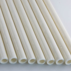 May include: A close-up of a group of white, round, hollow tubes. The tubes are arranged in a row, with the ends of the tubes facing the viewer.