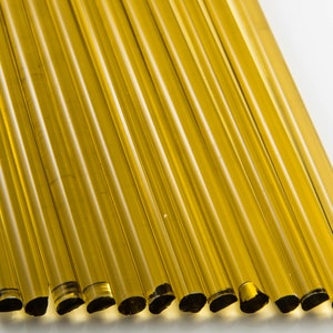 Könnte beinhalten: Ein Bündel aus 15 gelben Glasstäben mit schwarzen Enden. Die Stäbe sind in einer Reihe angeordnet, wobei die Enden der Stäbe zum Betrachter zeigen.