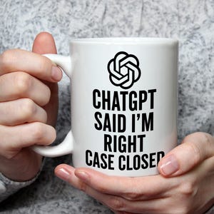 May include: White ceramic mug with the text "ChatGPT SAID I'M RIGHT CASE CLOSED" in black. The mug also features a black graphic. The mug is held by a person.