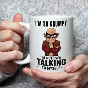 May include: White ceramic mug with a handle, featuring a cartoon illustration of a grumpy man with the text "I'M SO GRUMPY I'M NOT EVEN TALKING TO MYSELF" in black. The man is wearing glasses and a brown jacket.