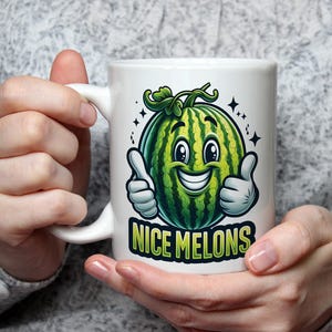 Op de afbeelding: Een witte keramische mok met een groene watermeloen-cartoonfiguur met een glimlachend gezicht en duimen omhoog. De tekst "NICE MELONS" is onder de watermeloen gedrukt.