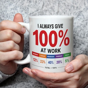 May include: White ceramic mug with the text "I ALWAYS GIVE 100% AT WORK." The mug features a breakdown of percentages for each day of the week, totaling 100%. The text is in black and red.