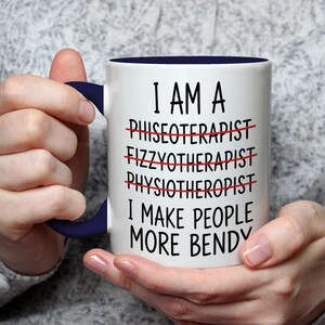 May include: White ceramic mug with a navy blue handle and interior. The mug features the text "I AM A PHYSIOTHERAPIST I MAKE PEOPLE MORE BENDY" with crossed-out words. A humorous gift for a physical therapist.