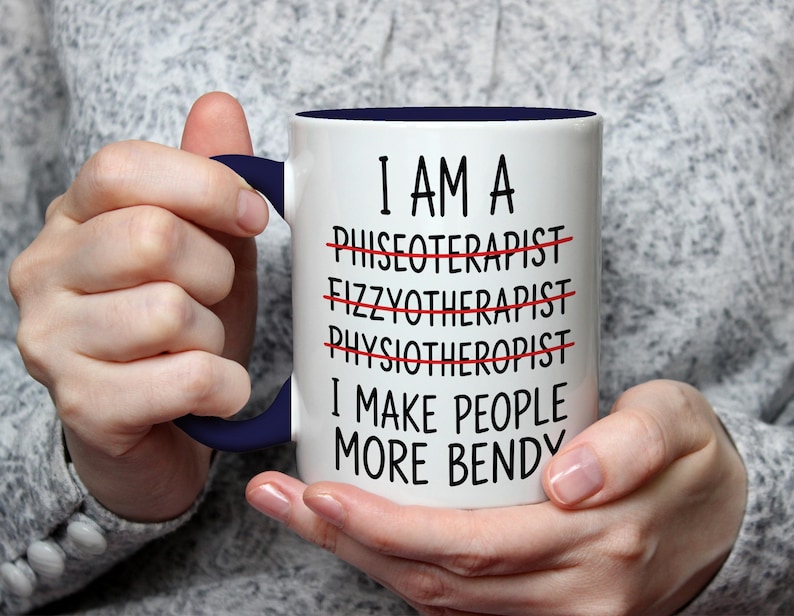 May include: White ceramic mug with a navy blue handle and interior. The mug features the text "I AM A PHYSIOTHERAPIST I MAKE PEOPLE MORE BENDY" with crossed-out words. A humorous gift for a physical therapist.