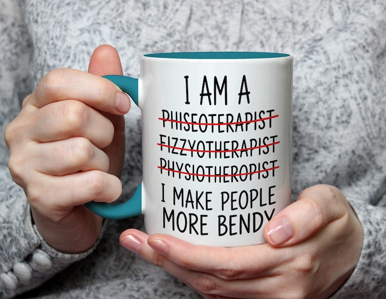 May include: White ceramic mug with a teal handle and interior. The mug features the text "I AM A... I MAKE PEOPLE MORE BENDY" with crossed-out words above. A humorous gift for a physical therapist.