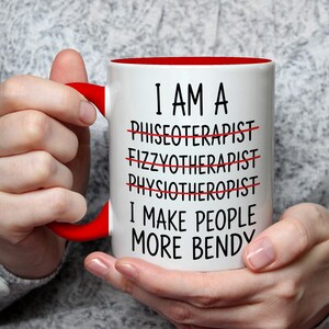 May include: White ceramic mug with a red interior and handle. The mug features the text "I AM A... I MAKE PEOPLE MORE BENDY" with crossed-out words. The mug is held by a person.