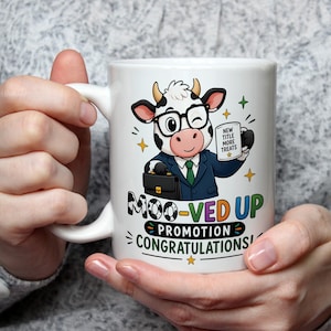May include: A white ceramic mug featuring a cartoon cow wearing glasses, a suit, and a tie, holding a briefcase and a small mug. The text reads MOO-VED UP PROMOTION CONGRATULATIONS and NEW TITLE MORE TREATS, surrounded by colourful star accents.