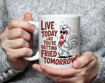 May include: White ceramic mug featuring a cartoon rooster wearing a cowboy hat and sunglasses. The mug has the text "LIVE TODAY LIKE YOU'RE GETTING FRIED TOMORROW" in brown lettering. The rooster is depicted in black and white.