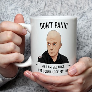 May include: White ceramic mug featuring the text "DON'T PANIC" and a cartoon image of a bald man. The text "NO I AM BECAUSE, I'M GONNA LOSE MY JOB" is below the image. The mug is held by a person.