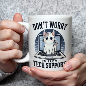 Op de afbeelding: Een witte keramische mok met een cartoonkat die op een laptop zit. De mok heeft de tekst "Maak je geen zorgen, ik ben van de technische ondersteuning".