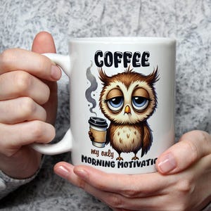 May include: White coffee mug featuring a cartoon owl holding a cup of coffee. The mug reads "Coffee, my only morning motivation."