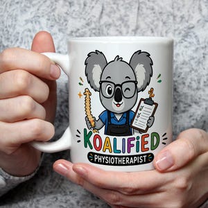 May include: A white ceramic mug featuring a cartoon koala wearing glasses and a blue shirt, holding a model of a human spine and a clipboard. The text KOALIFIED PHYSIOTHERAPIST is printed below the koala in colorful, bold lettering.