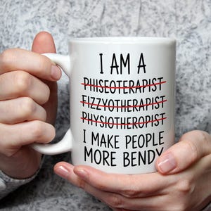 May include: White ceramic mug with black text: "I AM A... I MAKE PEOPLE MORE BENDY." The words "PHISEOTERAPIST," "FIZZYTHERAPIST," and "PHYSIOTHERAPIST" are crossed out in red. The mug is held by a person.