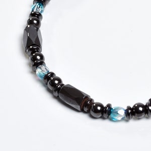 Op de afbeelding: Een zwarte kralen armband met blauwe kristallen accenten. De armband is gemaakt met ronde en rechthoekige kralen.