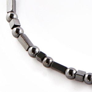 May include: A black beaded bracelet with alternating round and square beads.
