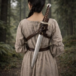 Może przedstawiać: Srebrny miecz ze szczegółową rękojeścią i ostrzem jest zabezpieczony w brązowej skórzanej pochwie i uprzęży. Miecz jest noszony na ramieniu osoby ubranej w długą, jasnobrązową sukienkę. Tło to rozmyty las.