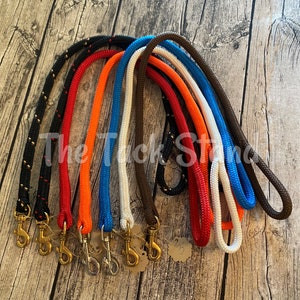 May include: A collection of colorful dog leashes in various shades, including black, red, orange, white, blue, and brown. Each leash features a rope design with a metal clasp. The text "The Tuck Stand" is visible.