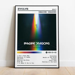 Könnte beinhalten: Ein gerahmtes Poster des Imagine Dragons Albums "Evolve" von 2017. Das Kunstwerk zeigt eine Person in einem Regenbogenlichtstrahl vor dunklem Hintergrund. Das Poster enthält den Albumtitel, den Bandnamen und eine Titelliste.