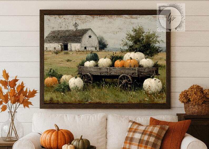 Op de afbeelding: Een ingelijste prent toont een rustieke herfstsc&egrave;ne. Een verweerde houten kar is gevuld met pompoenen in verschillende kleuren. Een witte schuur met een ster op de achtergrond, in een veld van groen en goud.