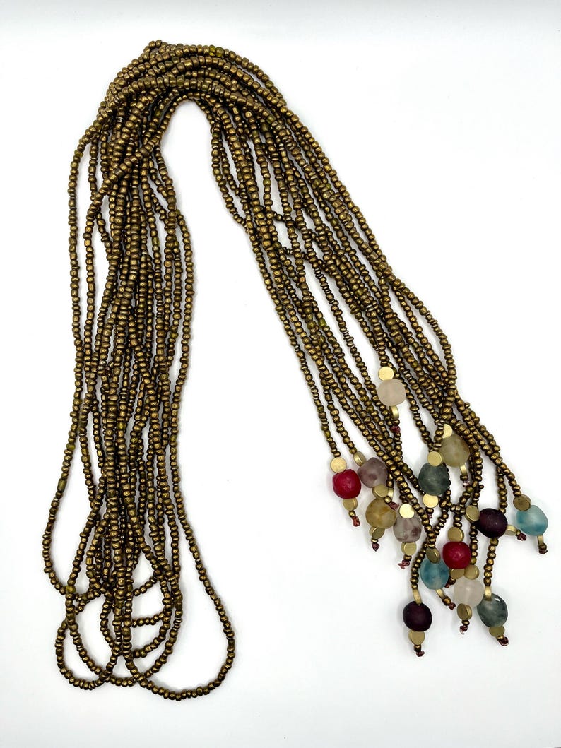 May include: A long gold beaded necklace with multiple strands and colorful glass beads at the end.