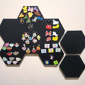 May include: Black hexagonal pin boards with various Disney character pins. The pins feature characters like Mickey Mouse, Minnie Mouse, and others. The pins are colorful and detailed, showcasing a variety of designs and themes.