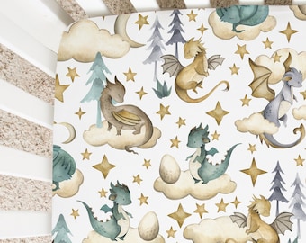 May include: A white crib sheet with a repeating pattern of dragons, stars, clouds, and trees. The dragons are in shades of blue, green, and brown. The stars are gold. The clouds are white with a light brown outline. The trees are green with a light blue outline.