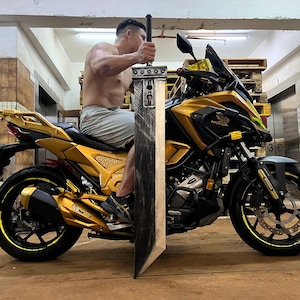 May include: A gold motorcycle with a black and silver sword leaning against it. The motorcycle has a black seat and a black and silver exhaust pipe. The sword is about 1.5 meters long.