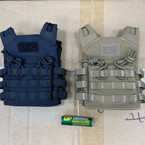 Op de afbeelding: Twee kleine tactische vesten, een zwarte en een bruine, met verstelbare banden en meerdere zakken.