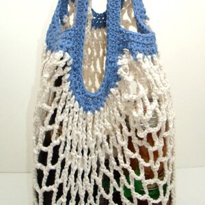 May include: A white crocheted string bag with blue handles. The bag is filled with a glass bottle and jars.